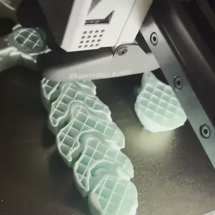 Long articulated dragon 3D print in mint color-shift filament, fresh off our printer bed