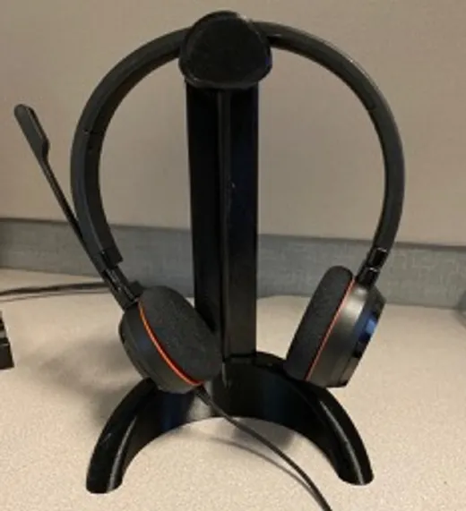 3D printed curved headphone stand holding a pair of over-ear headphones on a desk