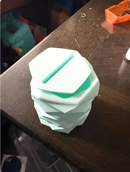 Top view of a mint green 3D printed geometric piggy bank showing the coin slot in its hexagonal lid