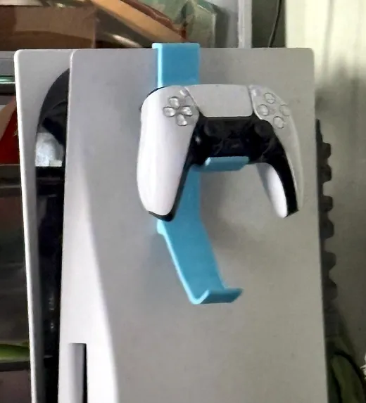 Light blue 3D printed wall mount holding a white game controller on the side of a console