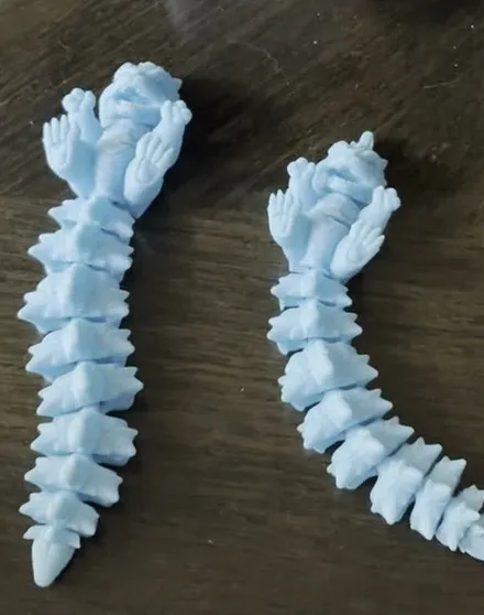 Two blue articulated spike dragon 3D prints resting on a wooden table
